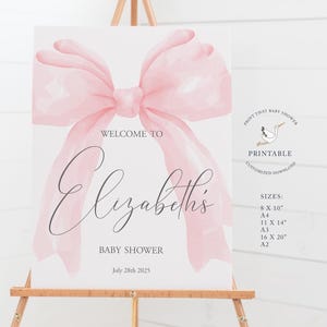 May include: Printable baby shower welcome sign with a pink watercolor bow, the text "Welcome to Elizabeth's Baby Shower" and the date "July 28th 2025".
