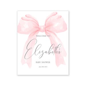 May include: A pink watercolor bow with a white background. The text "Welcome to Elizabeth's Baby Shower July 28th 2025" is printed below the bow.