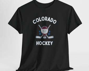 May include: Black t-shirt featuring the words "COLORADO HOCKEY" in white, with a hockey helmet, crossed hockey sticks, and blue stars. The design is centered on the front of the shirt.
