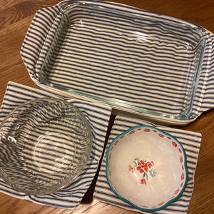 May include: Three fabric pot holders with blue and white stripes. The pot holders are designed to protect surfaces from hot dishes. One pot holder is large enough to fit a rectangular baking dish, while the other two are smaller and designed for bowls.