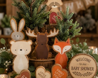 May include: A collection of wooden animal cutouts including a bear, moose, fox, rabbit, and raccoon, alongside heart-shaped signs labeled Baby Bear, Little Moose, and Sweet Little Fox, plus a round wooden sign reading Welcome to our Baby Shower.