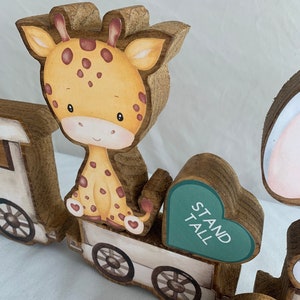 May include: Wooden train engine with a giraffe, a heart with the words "Stand Tall" and a white train car with wheels.