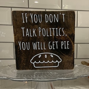 Peut inclure: Une pancarte en bois avec le texte "Si vous ne parlez pas de politique, vous aurez de la tarte." La pancarte est d&eacute;cor&eacute;e d'un contour blanc d'une tarte.