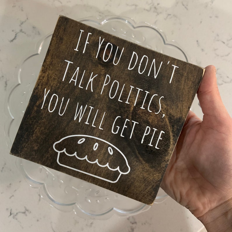 Peut inclure: Une pancarte en bois avec le texte "Si vous ne parlez pas de politique, vous aurez de la tarte" et un contour blanc d'une tarte.
