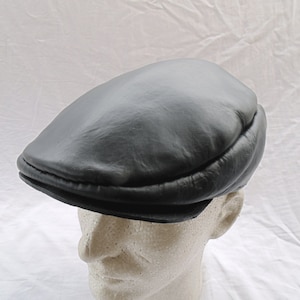 Peut inclure: Une casquette de newsboy en cuir noir avec une visière cousue.