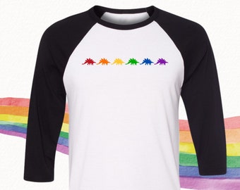 May include: A white and black baseball t-shirt with a row of rainbow colored dinosaurs on the front.