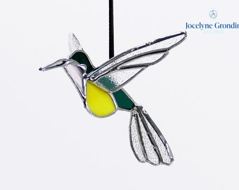 Stained glass hummingbird, 3D, it is green, pink and yellow, its wings are spread to fly, a beautiful glass suspension