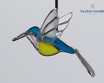 Stained glass hummingbird, 3D, it is blue, pink and yellow, its wings are spread to fly