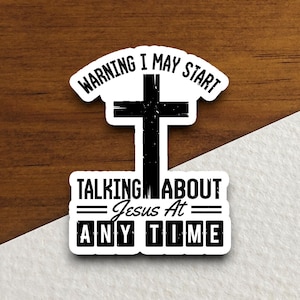 May include: A white sticker with black text and a black cross. The text reads "Warning I may start talking about Jesus at any time".
