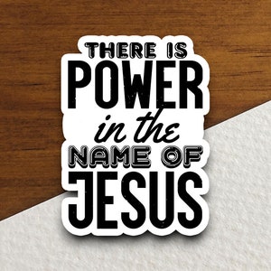May include: Black and white sticker with the text "There is power in the name of Jesus".