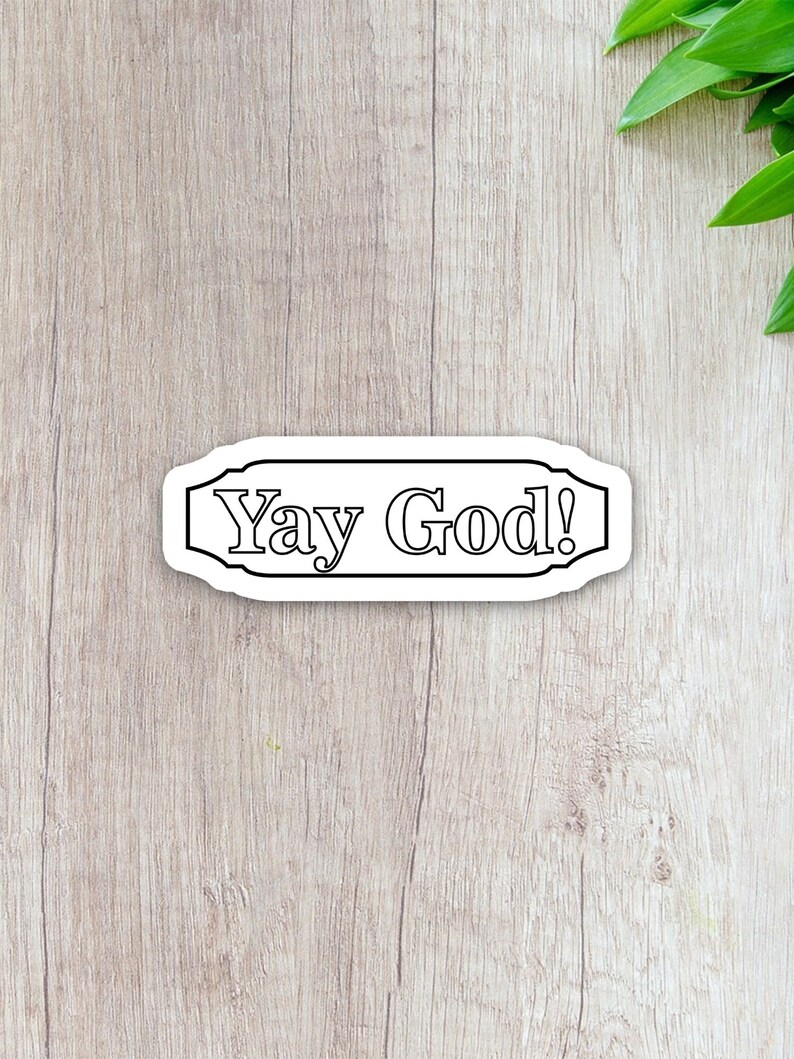 May include: A white sticker with black text that reads "Yay God!" The sticker is shaped like a banner with a decorative border.