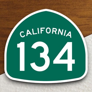 May include: A green California highway sign with white text and a white border. The sign reads "CALIFORNIA 134".