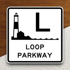 May include: A white sign with black text and a black and white illustration of a lighthouse and a wave. The sign reads "LOOP PARKWAY".