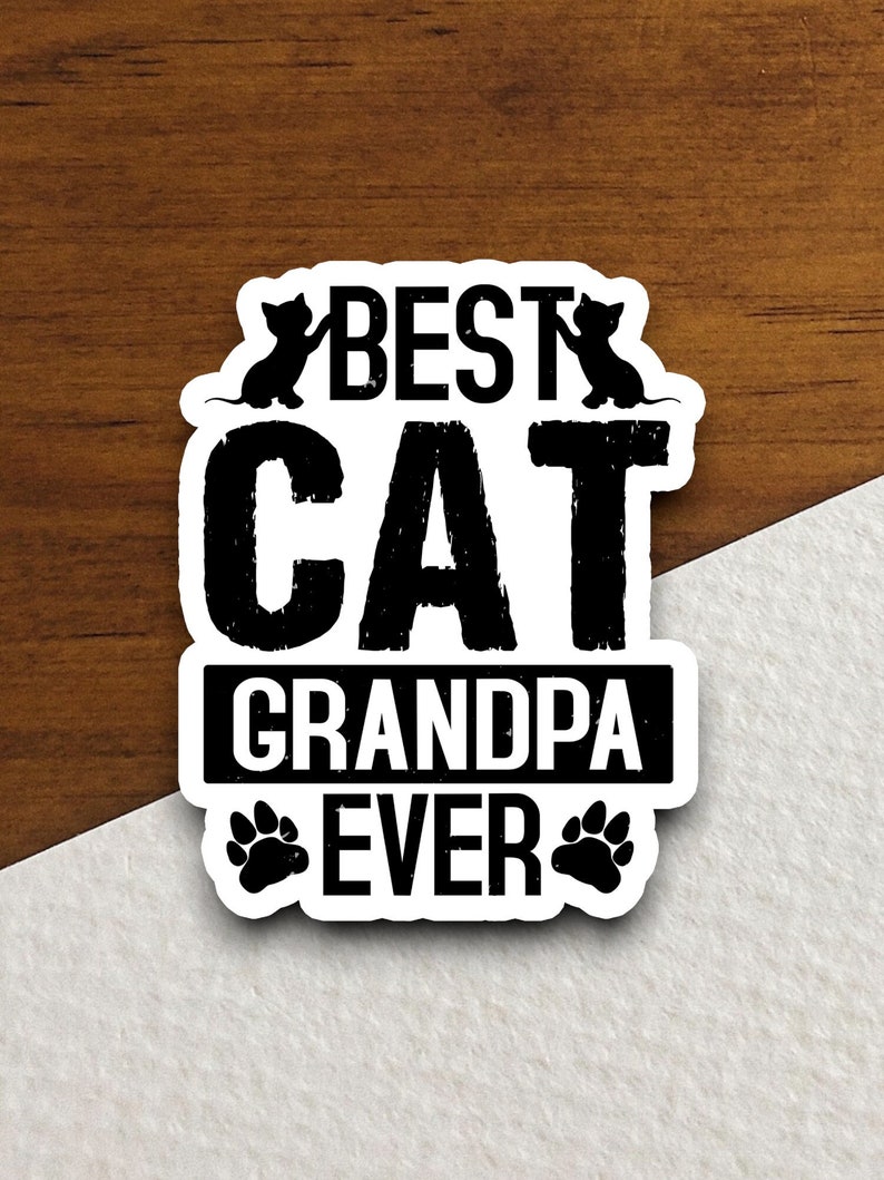 Pu&ograve; includere: Adesivo bianco e nero con il testo "Best Cat Grandpa Ever" in un font usurato. Due silhouette di gatti neri sono sopra il testo e due impronte di zampe nere sono sotto il testo.