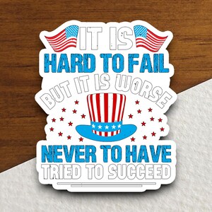 May include: A white sticker with a red, white, and blue American flag design. The sticker features the text "IT IS HARD TO FAIL BUT IT IS WORSE NEVER TO HAVE TRIED TO SUCCEED".