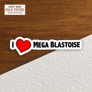 May include: A rectangular sticker featuring the text I, a red heart symbol, and the text MEGA BLASTOISE in black capital letters. The sticker has a white border and is positioned against a split background of dark wood grain and white texture.