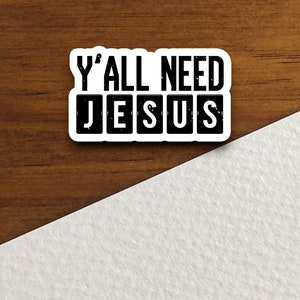 Peut inclure: Un autocollant blanc avec du texte noir qui dit "Y'all need Jesus" dans une police de caract&egrave;res en d&eacute;tresse.