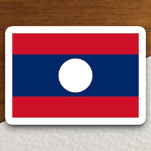May include: A sticker featuring the flag of Laos. The flag is red, blue, and white with a white circle in the center.