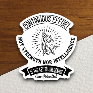 May include: Black and white sticker with a quote about continuous effort being the key to unlocking potential. The quote reads "Continuous Effort Not Strength Nor Intelligence Is The Key To Unlocking Our Potential". The sticker features a drawing of hands clasped in prayer with a rosary.