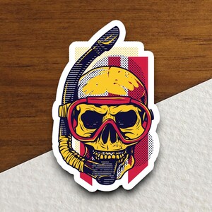 May include: A sticker featuring a yellow skull wearing a red diving mask and a yellow snorkel. The skull is set against a red and white striped background.