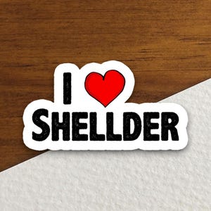May include: A white sticker with a red heart and the text "I love Shellder".