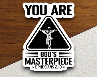 May include: Black and white sticker with a triangle warning sign. The sign has a silhouette of a person on a cross. The text reads "You Are God's Masterpiece Ephesians 2:10".