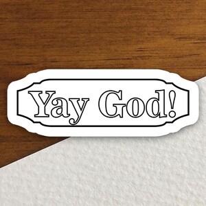 May include: White sticker with black outline and the text "Yay God!" in a decorative font.