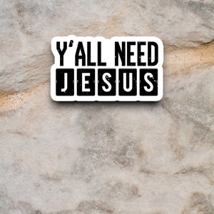 Peut inclure: Un autocollant blanc avec du texte noir qui dit "Y'all need Jesus" sur un fond textur&eacute; gris.