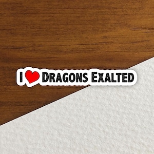 Puede incluir: Una pegatina blanca con el texto "I ❤️ DRAGONS EXALTED". El corazón es rojo y el texto es negro. La pegatina está sobre una superficie de madera con un fondo blanco en ángulo.