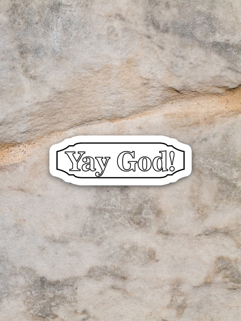May include: A white sticker with black text that reads "Yay God!" on a textured, light brown background.