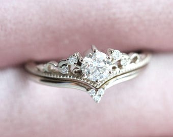 May include: A delicate silver ring set with a large, round, clear diamond. The ring features a delicate, ornate design with smaller diamonds set around the main stone.