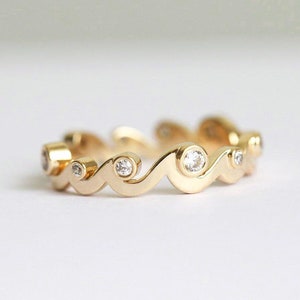 Yellow gold band with diamonds styled as a ocean waves.