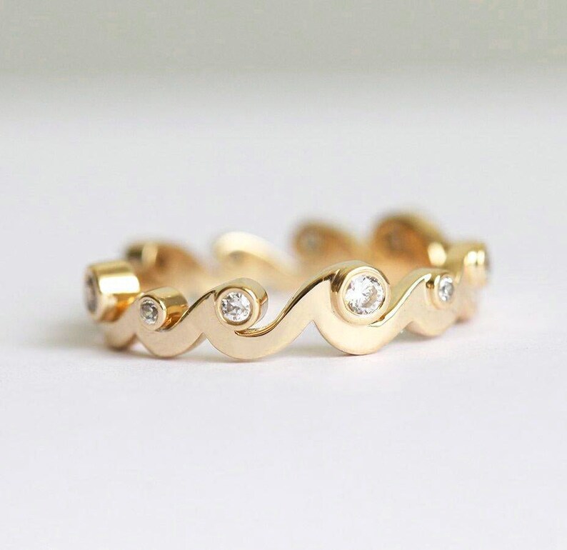 Yellow gold band with diamonds styled as a ocean waves.