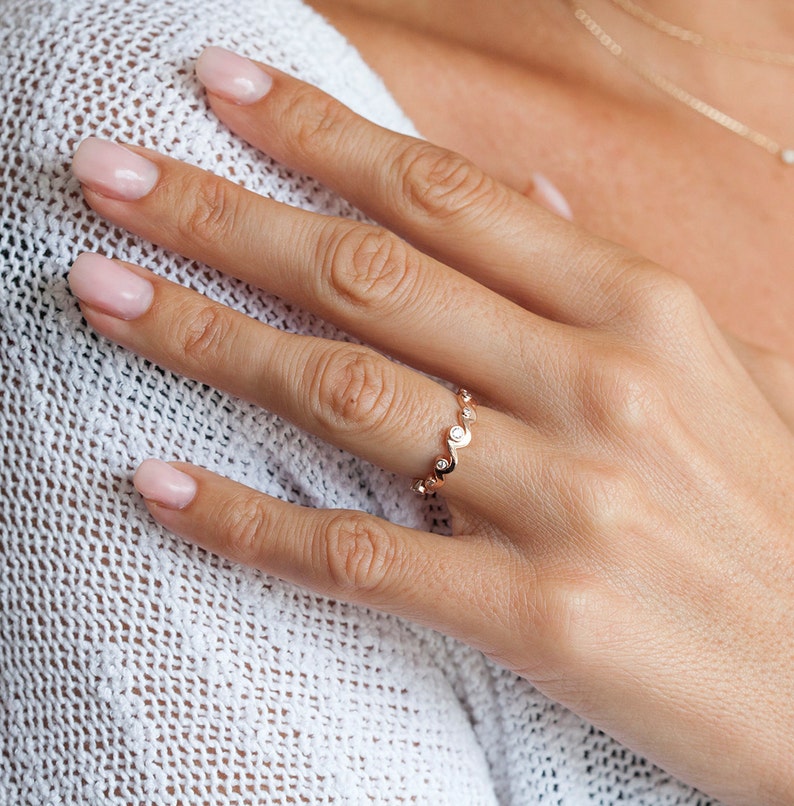 Rose gold band with diamonds styled as a ocean waves.