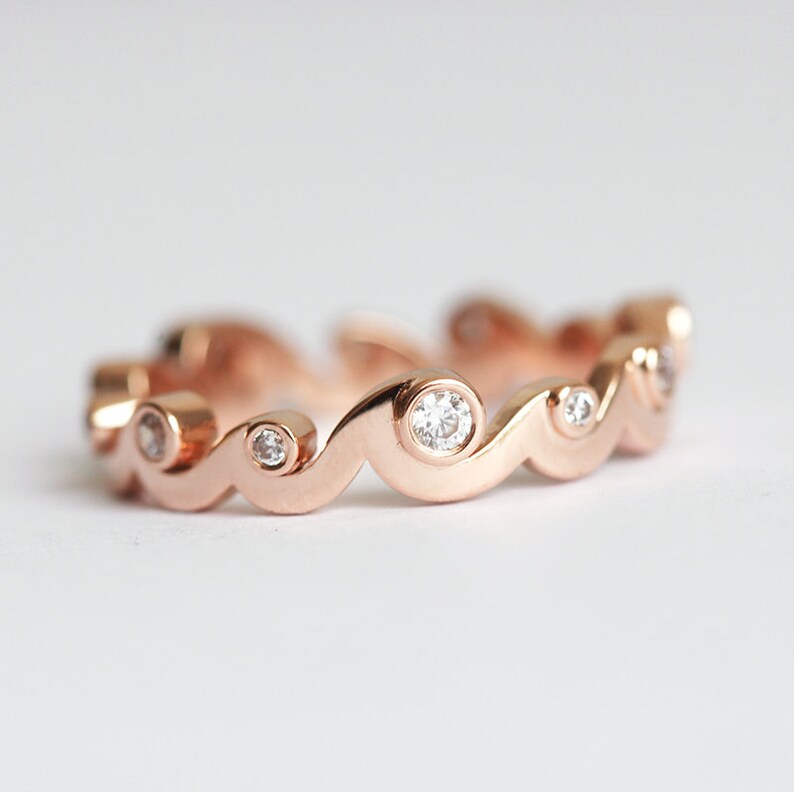 Rose gold band with diamonds styled as a ocean waves.