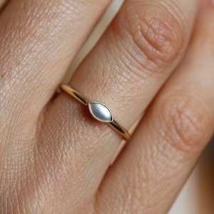 Peut inclure: Une délicate bague en or avec une pierre ovale perlée au centre.