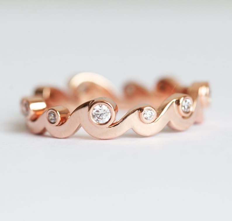 Rose gold band with diamonds styled as a ocean waves.