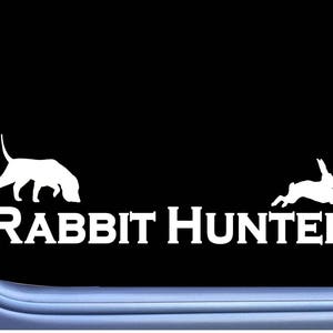 May include: White vinyl decal of a rabbit and a dog with the text "Rabbit Hunter" on a black background.