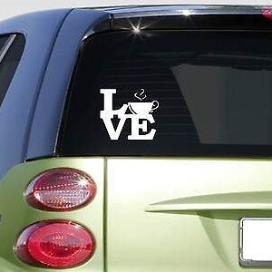 May include: White vinyl decal with the word "LOVE" with a coffee cup replacing the "O". The decal is on the back window of a green car.
