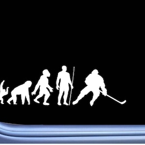 May include: White evolution of hockey player decal on a black background. The decal shows the evolution of man from ape to hockey player, with a hockey stick and gear.