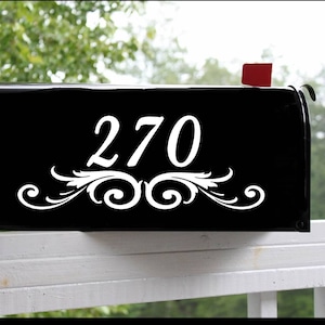 Op de afbeelding: Zwarte brievenbus met het witte nummer 270 en een decoratief krulontwerp.