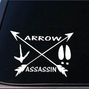May include: White vinyl decal with two crossed arrows, a bird footprint, and a deer footprint. The text "ARROW ASSASSIN" is written below the arrows.