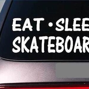 May include: White vinyl decal sticker with the text "Eat - Sleep Skateboard" on a black car window.