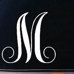 May include: White vinyl decal of the letter M with a decorative flourish. The letter is in a script font and is suitable for a car window or other smooth surface.