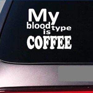 May include: White vinyl decal with the text "My blood type is COFFEE" in a bold, sans-serif font. The decal is designed to be applied to a car window or similar surface. The text is arranged in three lines.