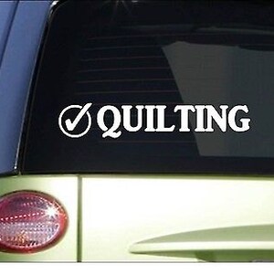 May include: White vinyl decal with a checkmark and the word "QUILTING" on a green car window.