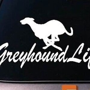May include: White vinyl decal of a greyhound running with the text "Greyhound Life" in a cursive font.