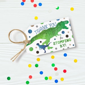 May include: Thank you for stopping by! Green and blue dinosaur silhouette on a white tag with brown, black, and silver polka dots. The tag has a brown twine loop.