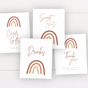 Op de afbeelding: Vier witte borden met een regenboogontwerp en tekst. De borden tonen "Cards & Gifts", "Sweet Treats", "Drinks" en "Thank you! We hope you had fun - Please take one!"