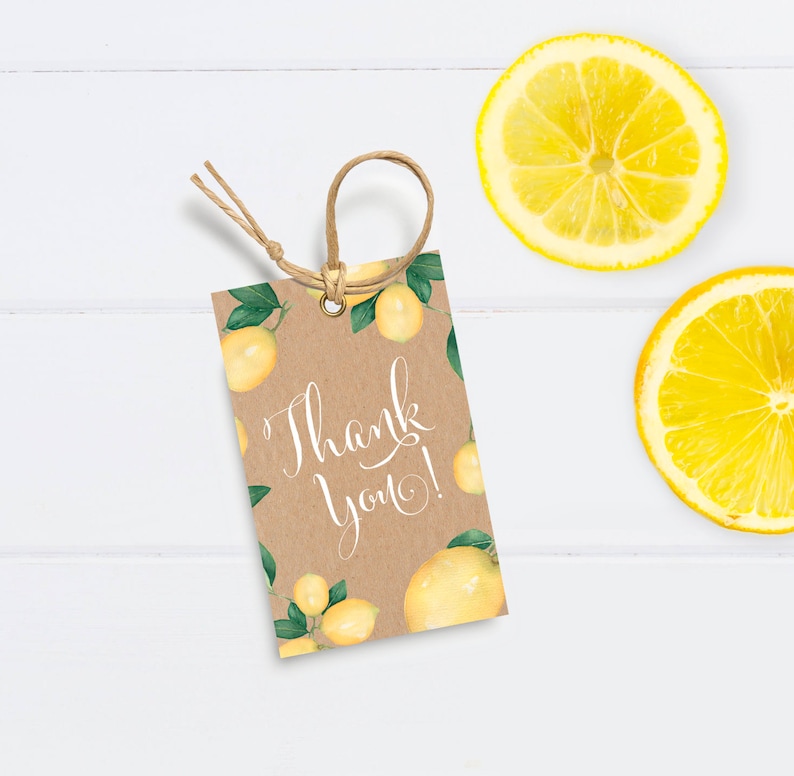 May include: A brown kraft paper gift tag with a lemon theme. The tag has a white background with the text "Thank you!" and is decorated with yellow lemons and green leaves. The tag is tied with twine.